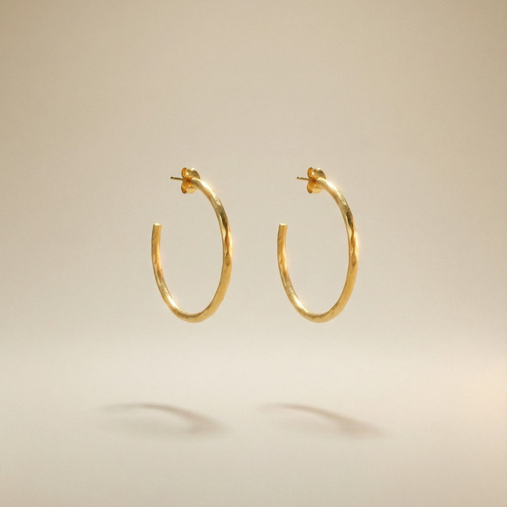 18 karat goldene Creoloen mit mattemfinish auf beigem Hindergrund