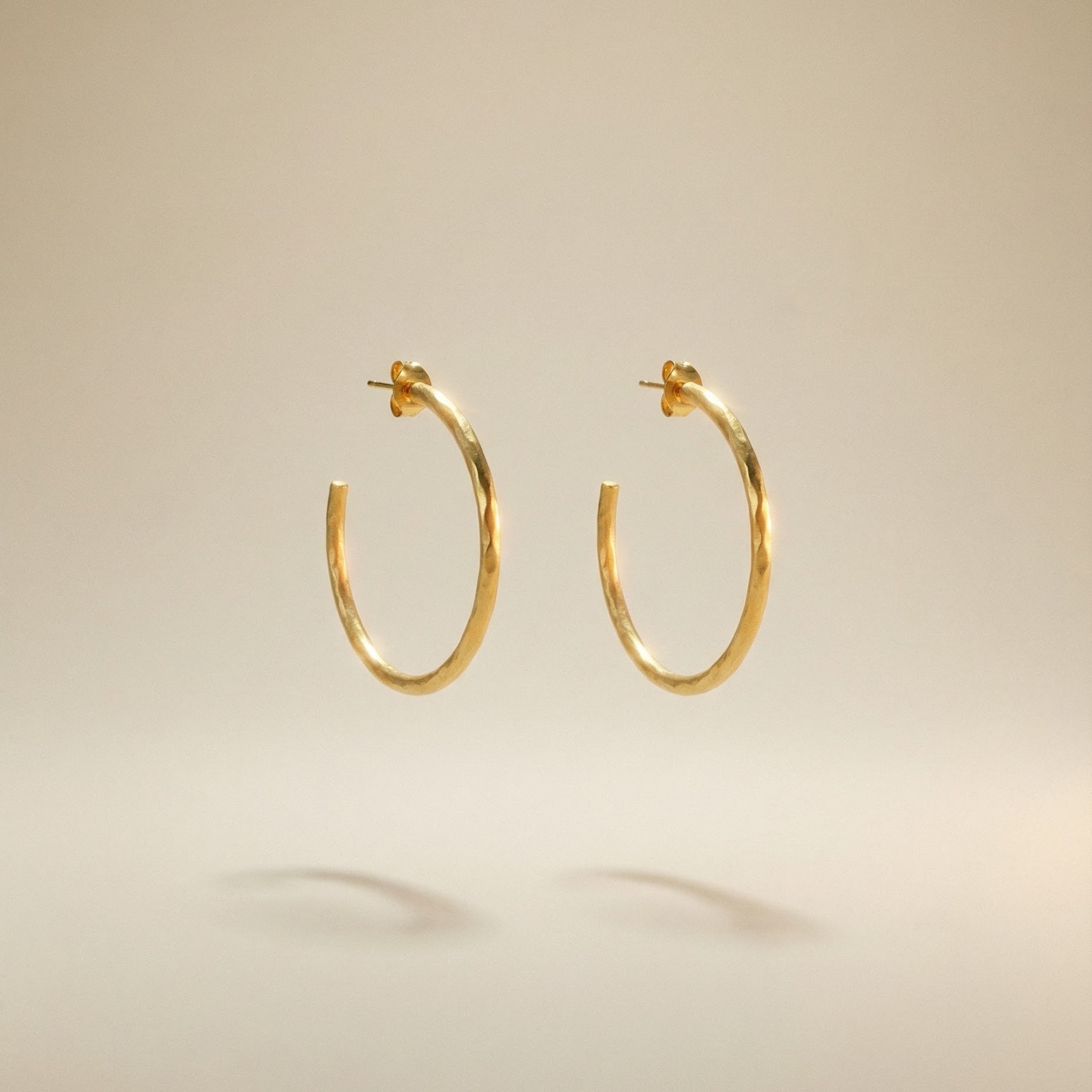 18 karat goldene Creoloen mit mattemfinish auf beigem Hindergrund