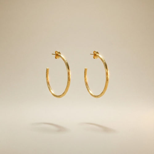 18 karat goldene Creoloen mit mattemfinish auf beigem Hindergrund