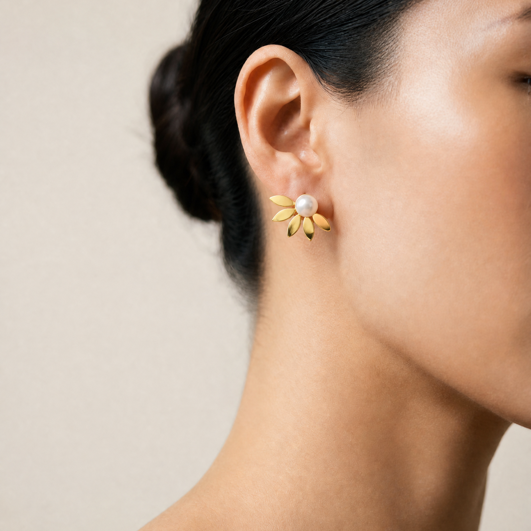 Close up von Süsswasserperlen Ohrringen mit golidgem Fächer an einer Frau mit Sleek bun