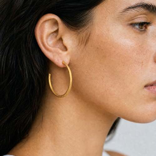 Profil einer dunkelhaarigen Frau closeup eines  goldenen Hoop Ohhring mit strukturiertem matten finish 