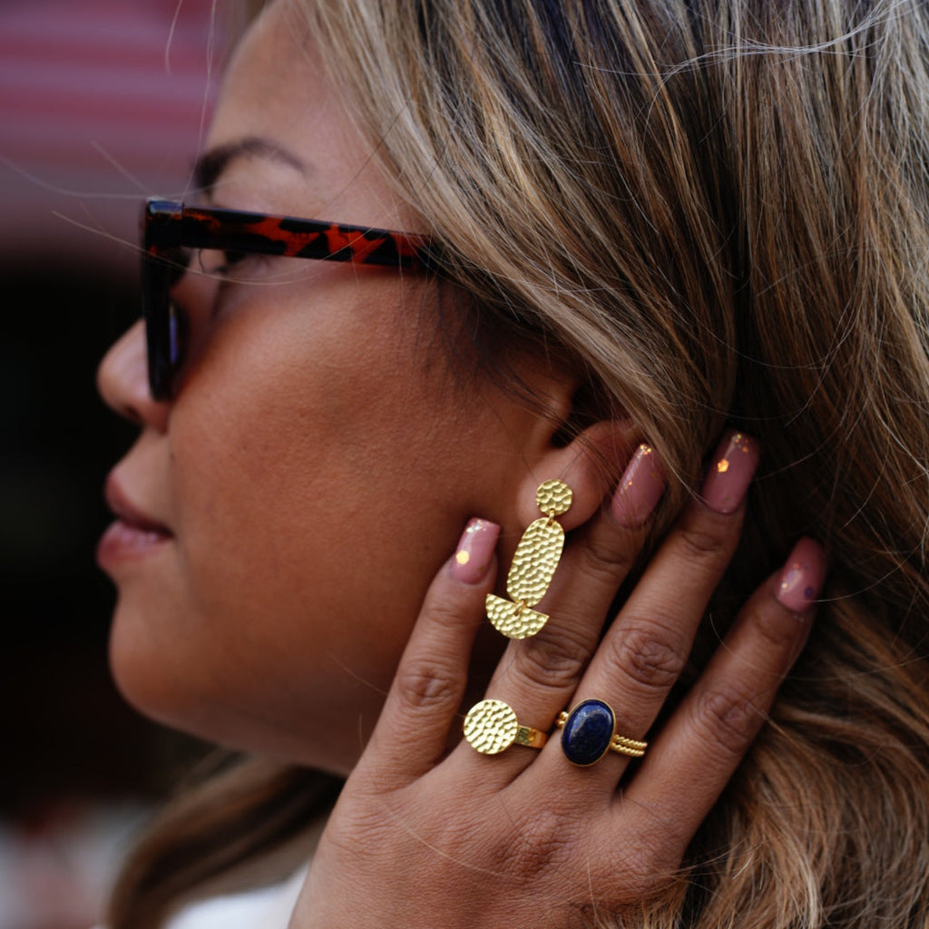 Close up von einer Frau mit Sonnenbrille die Schmuck trägt.