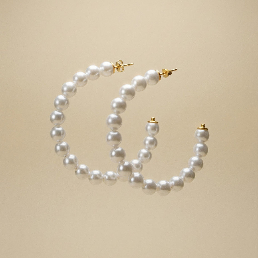 Creolen mit Süsswasserperlen bestezt auf beigem Hintergrund.