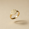 Goldener Ring mit handgehämmerter Textur auf dem Siegel auf beigem Hintergrund
