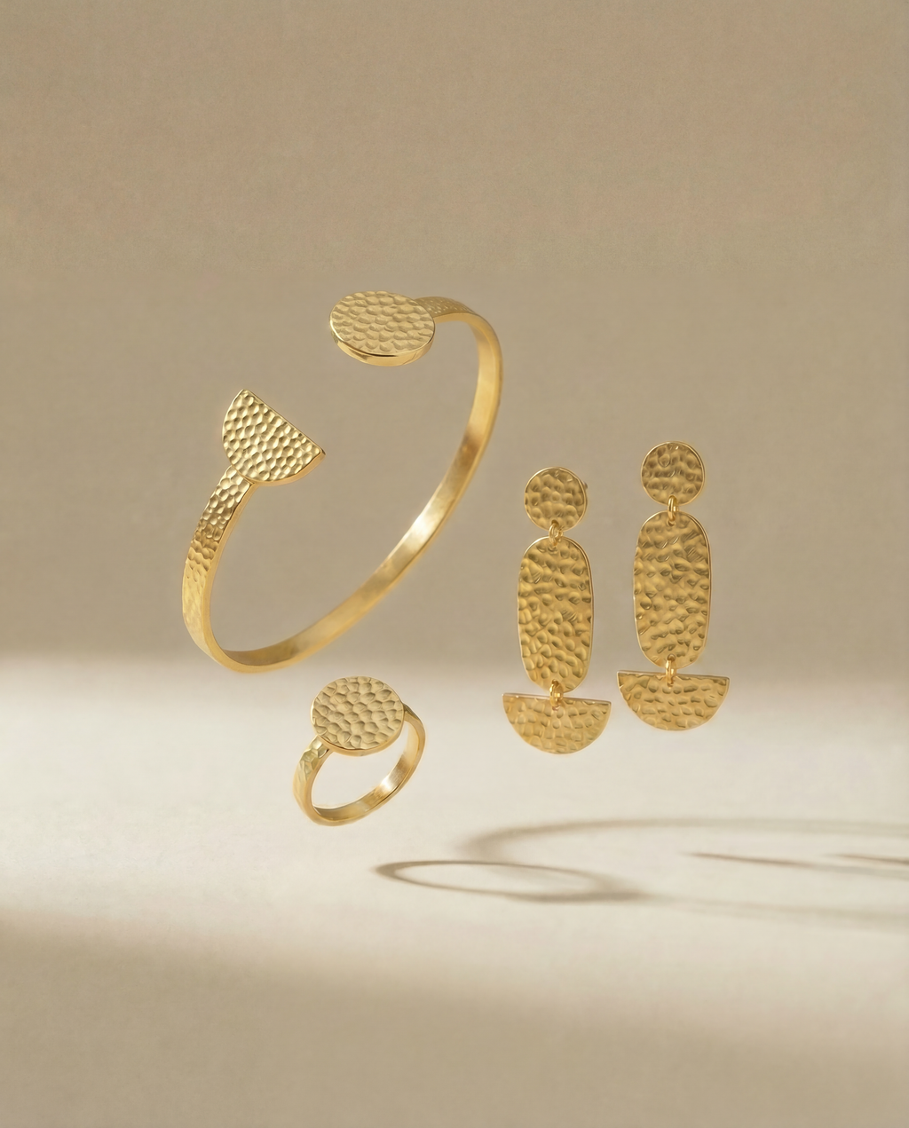 Schmuck set aus drei Teilen, Armreif, Ohrringe, Ring auf beigem Hintergrund