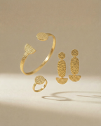Schmuck set aus drei Teilen, Armreif, Ohrringe, Ring auf beigem Hintergrund