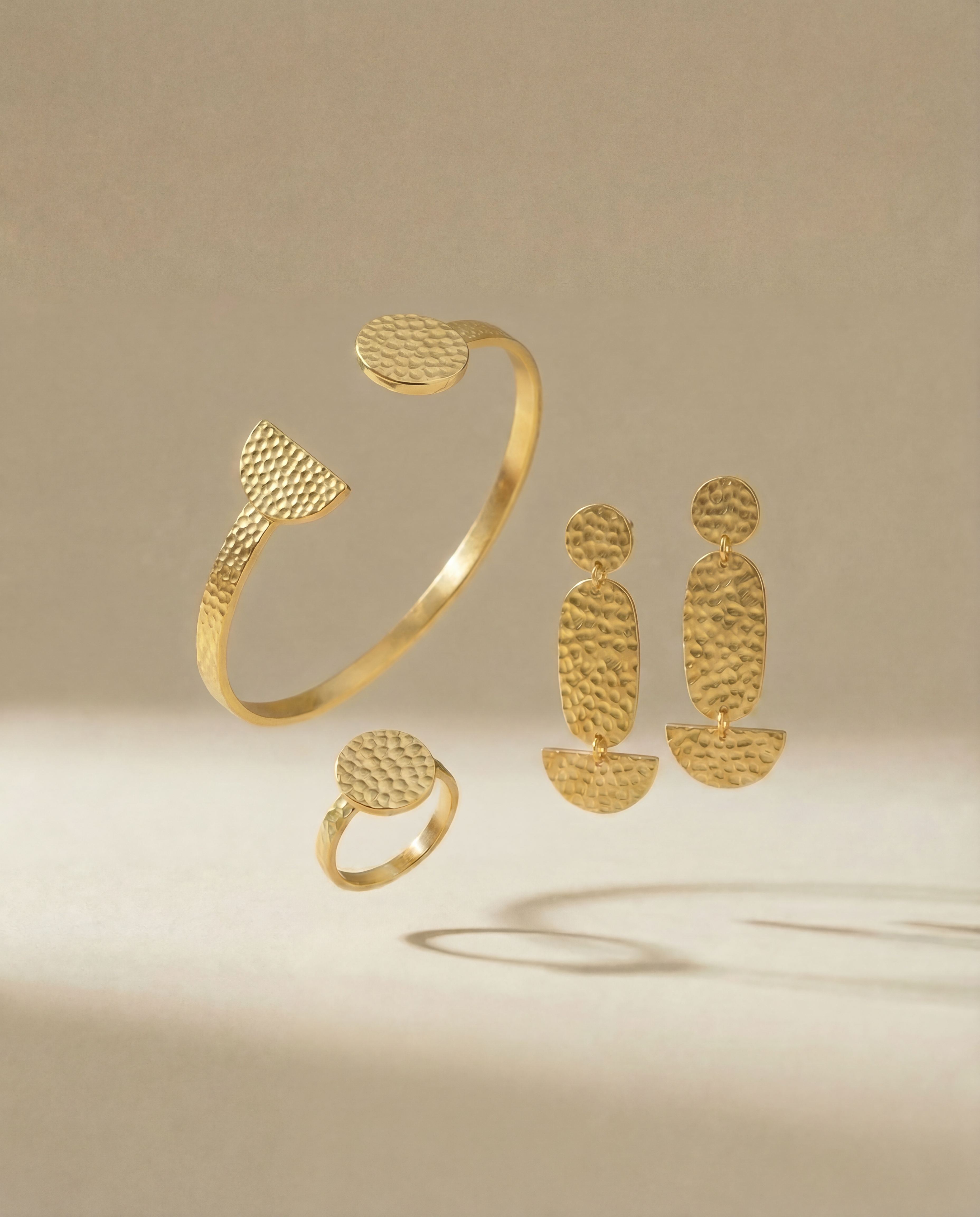 Schmuck set aus drei Teilen, Armreif, Ohrringe, Ring auf beigem Hintergrund