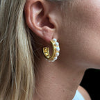 Close Up eines Ohrrings. Goldene Creolen mit Süsswasserperlenbesetzt an einem Ohr